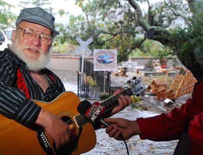 man playing guitar in fron of a g-scale layout