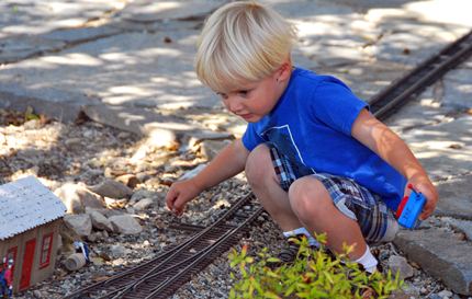 child throwing a switch on a g-scale layout