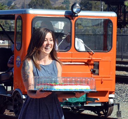 woman carrying a celebration cake past an orange speeder