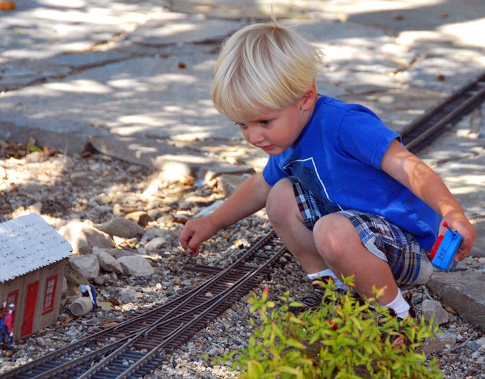 child throwing a switch on a G-scale railroad